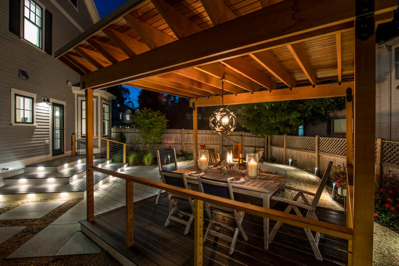 View of a wood pergola with an outdoor table and lighting
