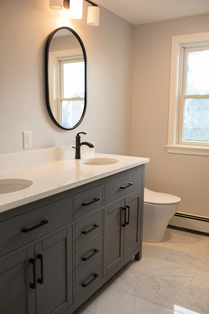 Elegant bathroom renovation in Arlington, MA, with a dual-sink vanity, black hardware, and soft neutral tones