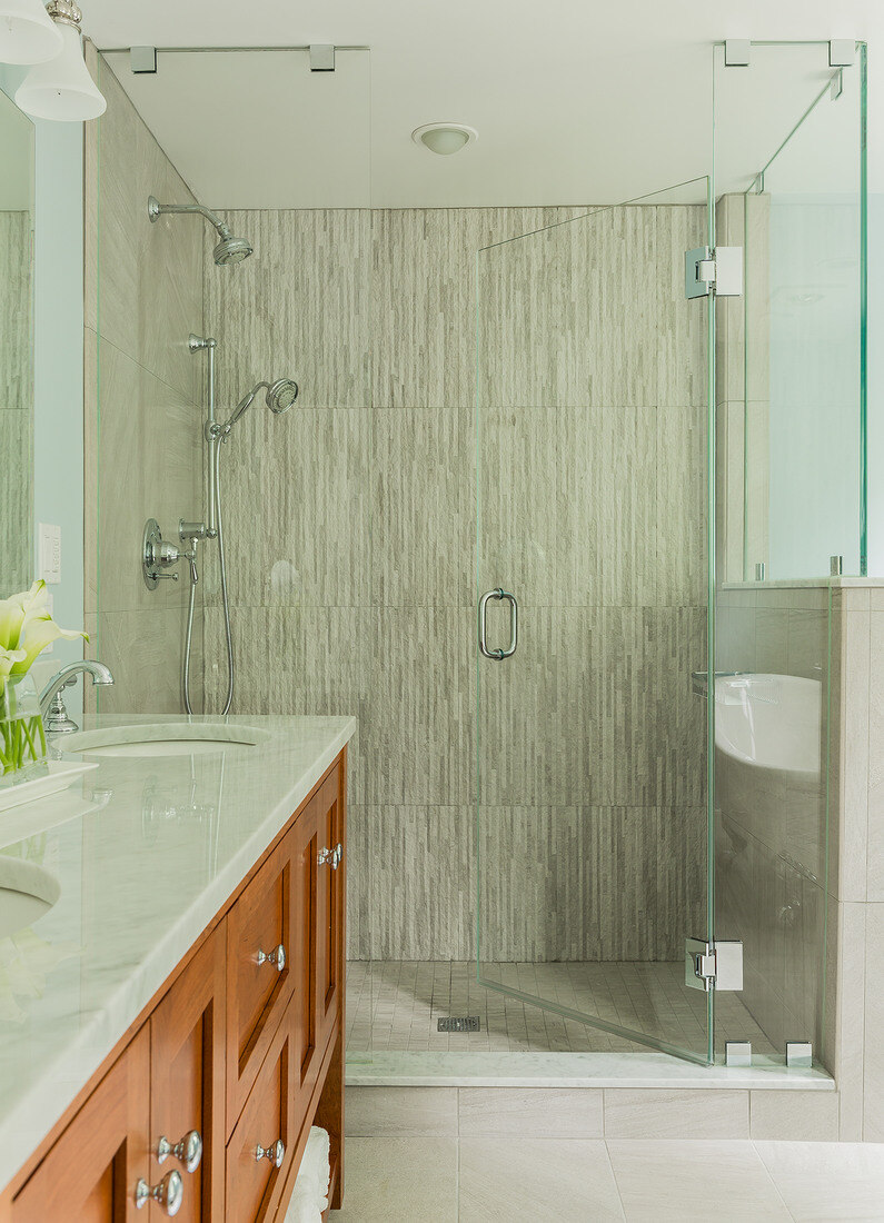 Stylish walk-in shower in a Lexington, MA bathroom remodel by Tom Curren, featuring sleek floor-to-ceiling tile and a frameless glass door