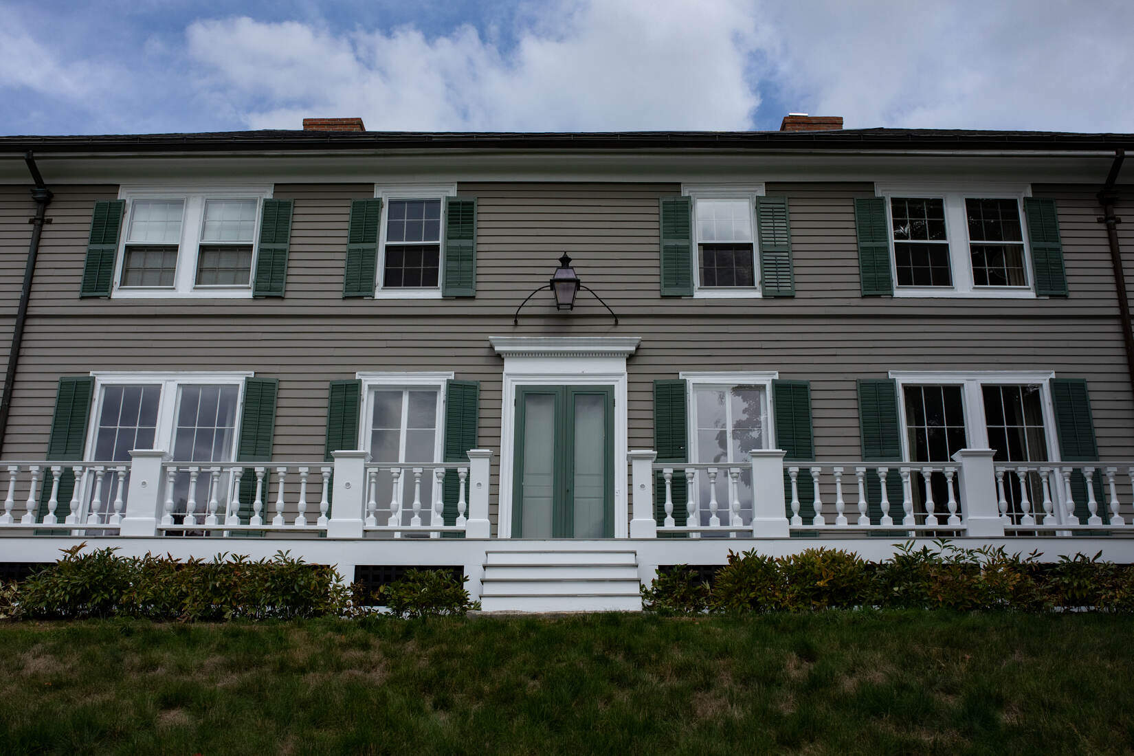 Wide-angle view of a historic home with freshly painted railings and a deck, renovated by Tom Curren in Lincoln, MA