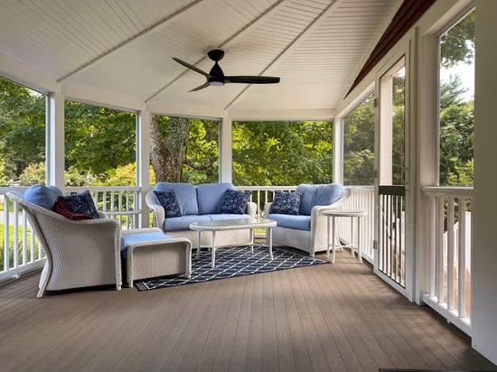 Spacious wooden deck with lounge seating and an umbrella, remodeled by Tom Curren in Medfield, MA