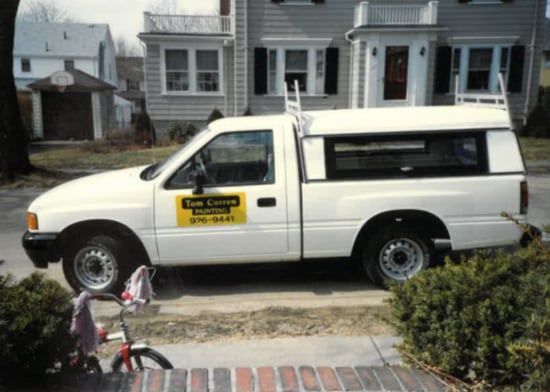 Early Tom Curren Companies pickup truck with original yellow logo parked in front of a home, reflecting the company’s local painting beginnings