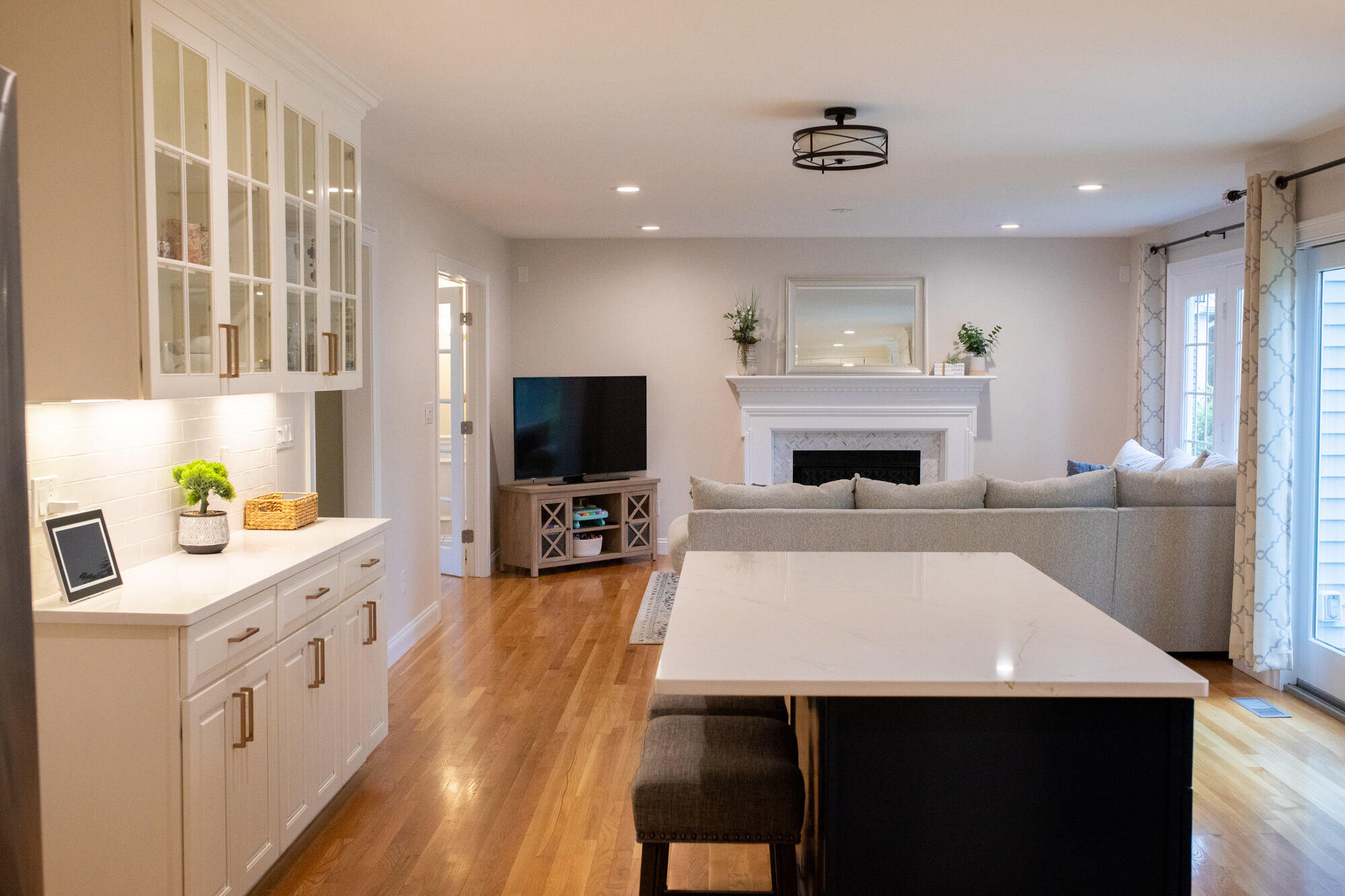 Modern kitchen and living room with fresh neutral paint and a fireplace feature wall in Framingham, MA