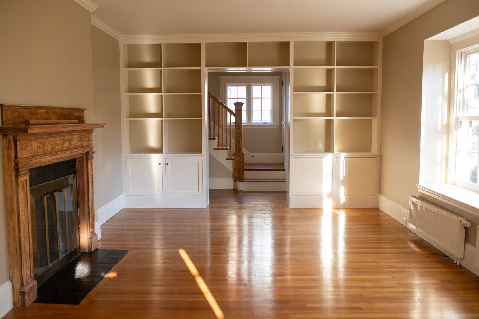 Classic living room in Cambridge, MA with newly painted walls, a wood fireplace, and built-in shelving
