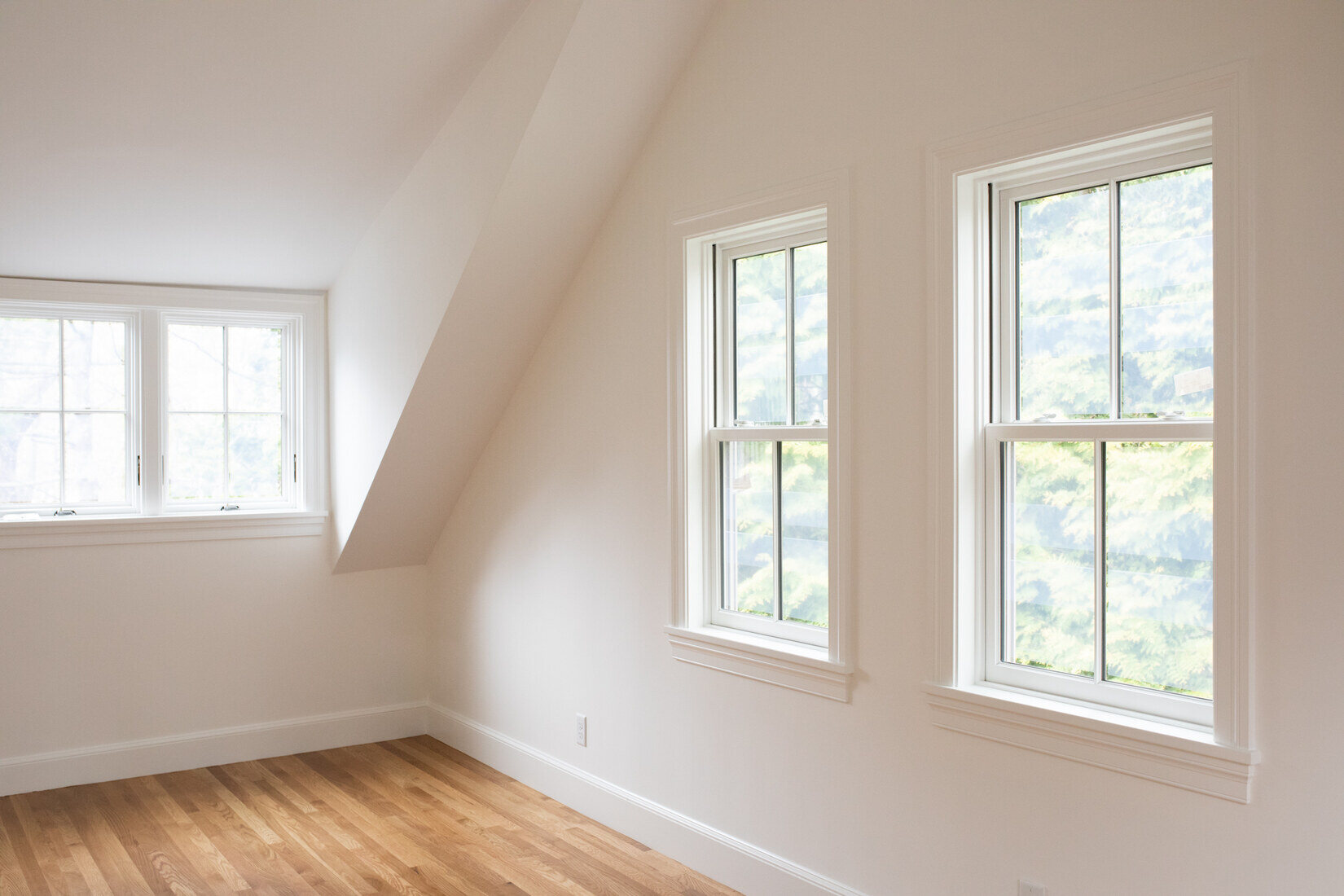 Freshly painted attic space in Lincoln, MA, featuring white walls, large windows, and bright hardwood floors by Tom Curren