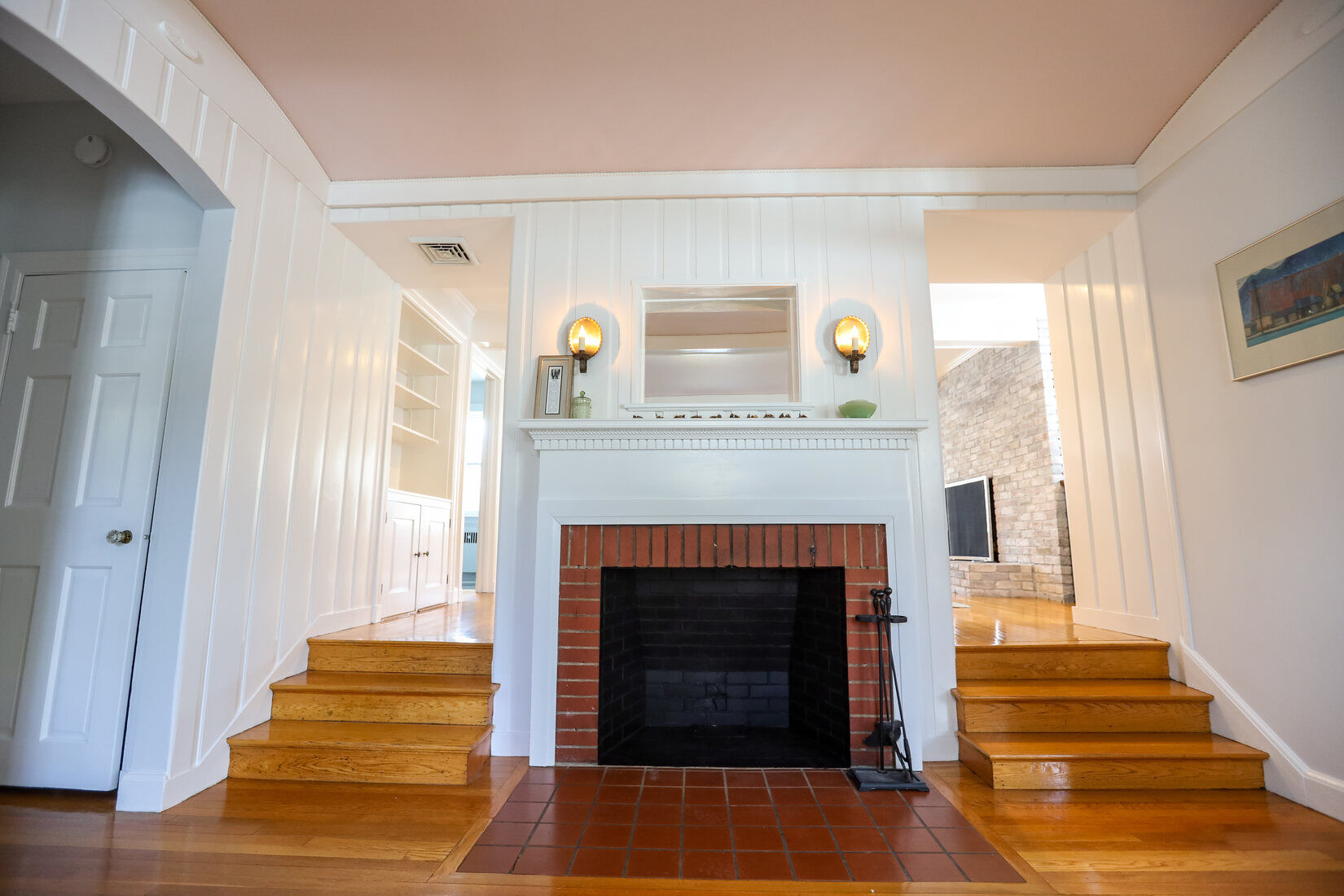 Freshly painted white paneling and brick fireplace in a bright, updated living space in Lincoln, MA by Tom Curren