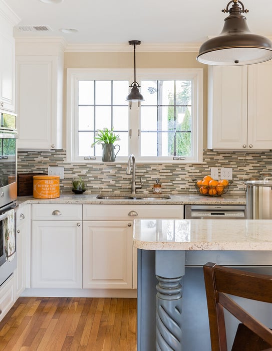 Belmont, MA kitchen remodel by Tom Curren featuring a charming farmhouse-style sink, white cabinets, and a glass tile backsplash