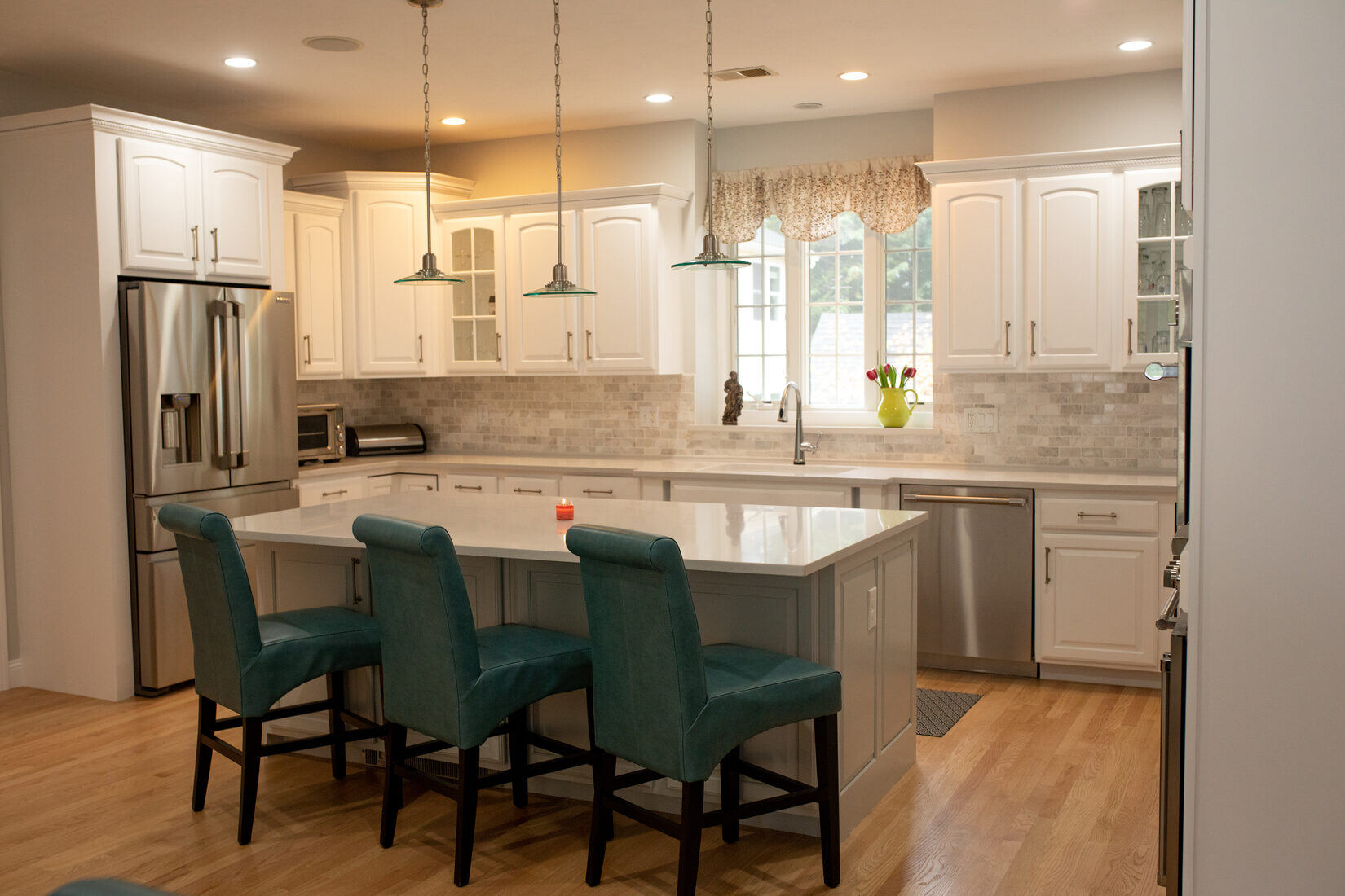 Close-up of a beautifully remodeled kitchen in Lexington, MA by Tom Curren, highlighting white painted cabinets and a modern backsplash