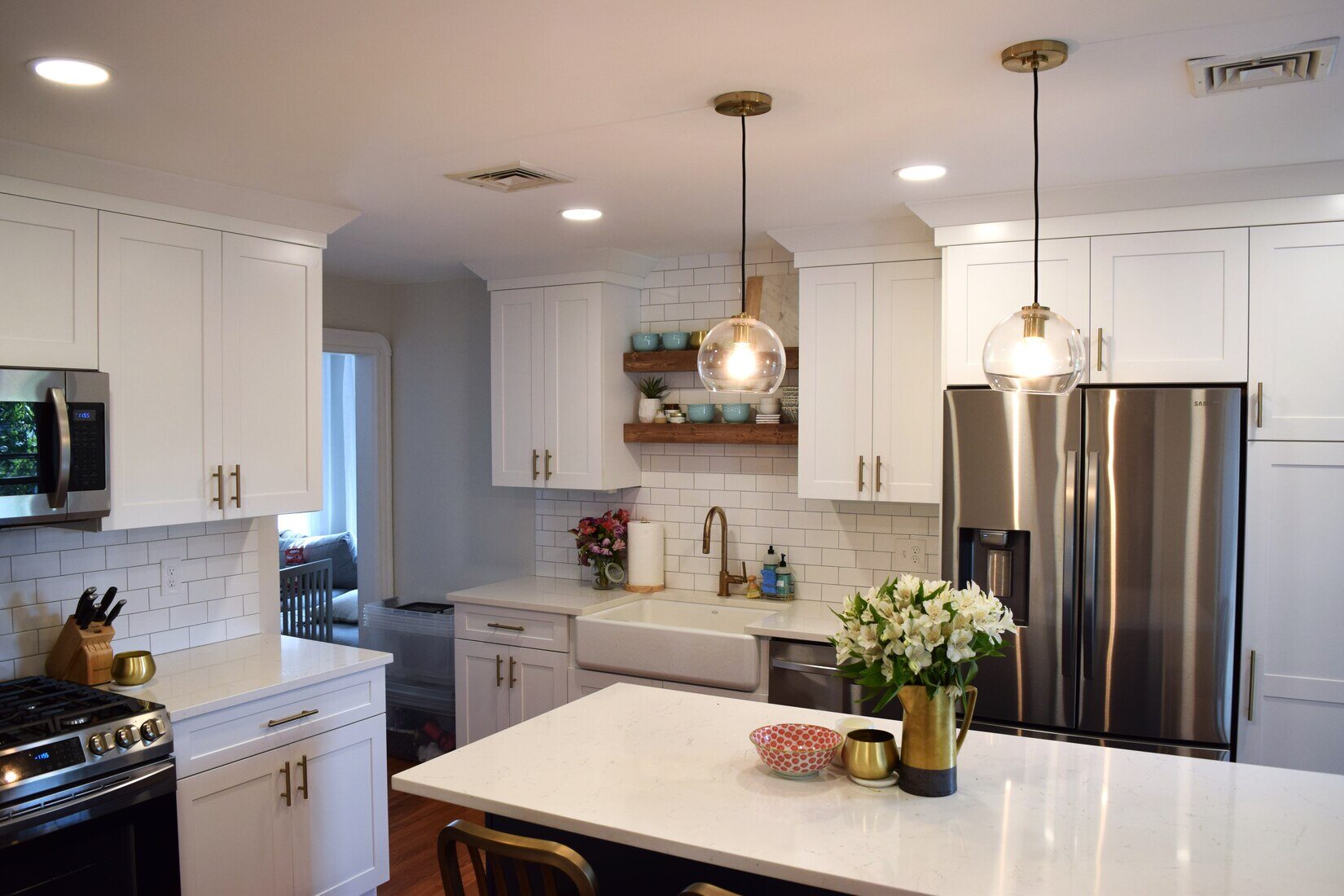 Elegant kitchen remodel in Somerville, MA featuring a white island, gold pendant lighting, and stainless steel appliances