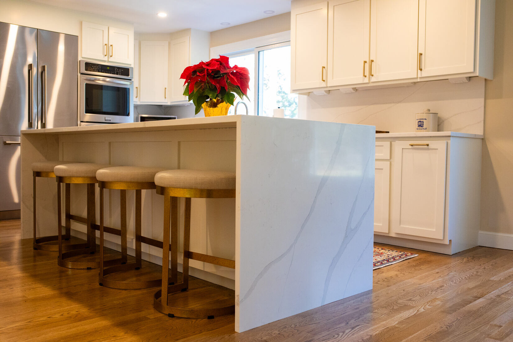 Modern white kitchen remodel in Sudbury, MA, incorporating gold hardware and a waterfall countertop