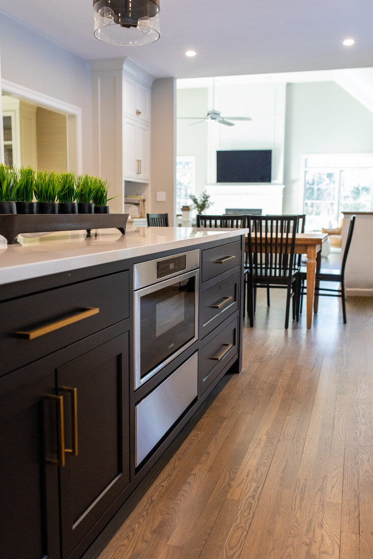 Open-concept kitchen remodel in Bedford, MA by Tom Curren, connecting the kitchen to the dining and living area with a sleek island