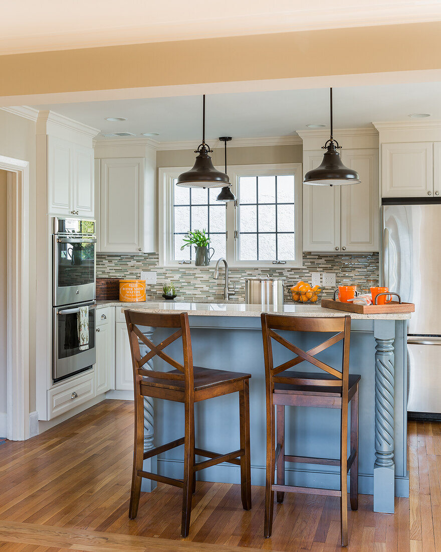 Stylish Belmont, MA kitchen remodel by Tom Curren with a blue island, white cabinets, and hardwood flooring