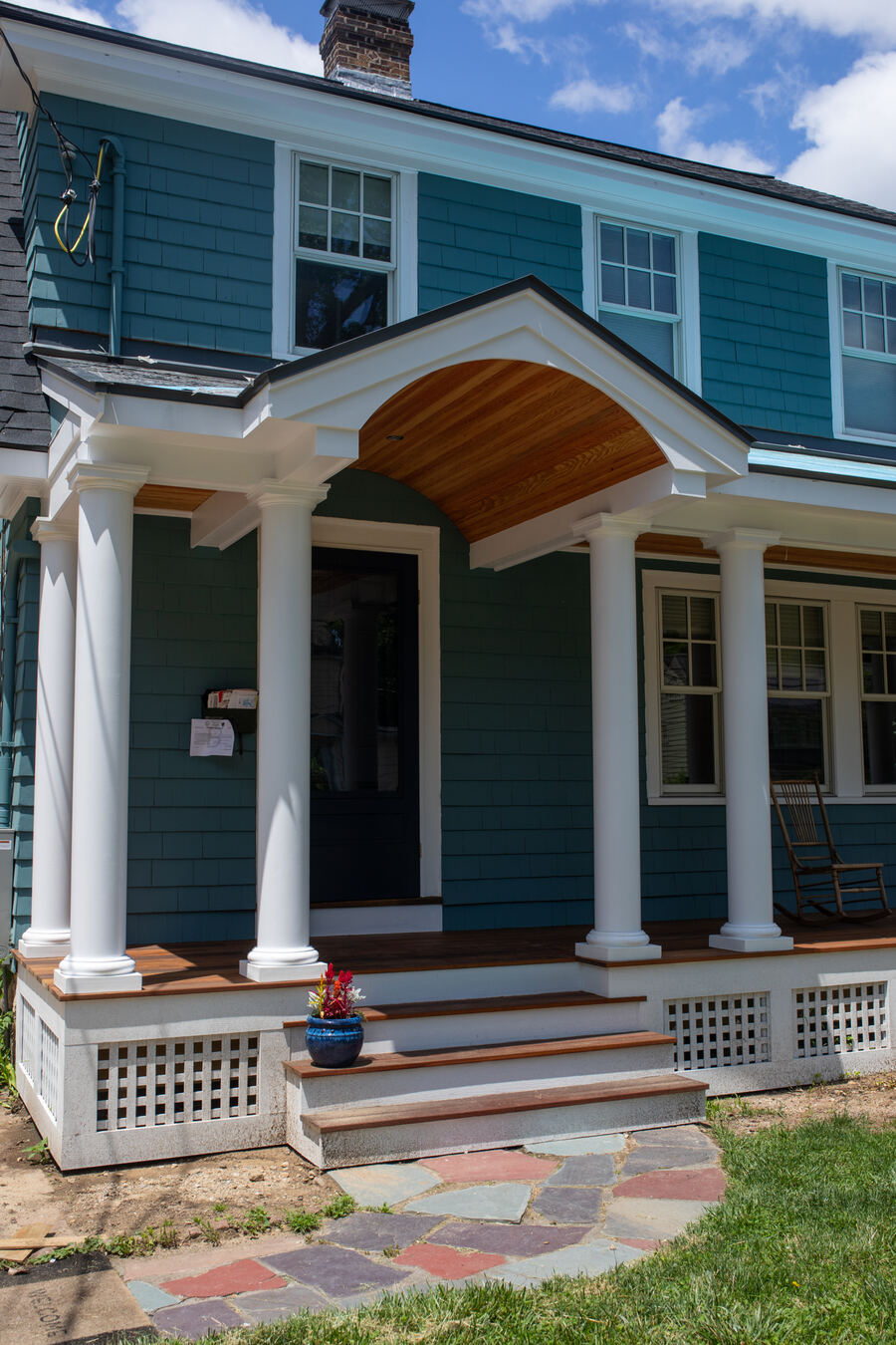 Recently remodeled front porch with white columns and a natural wood ceiling beneath a gabled roof, showcasing updated craftsmanship and curb appeal