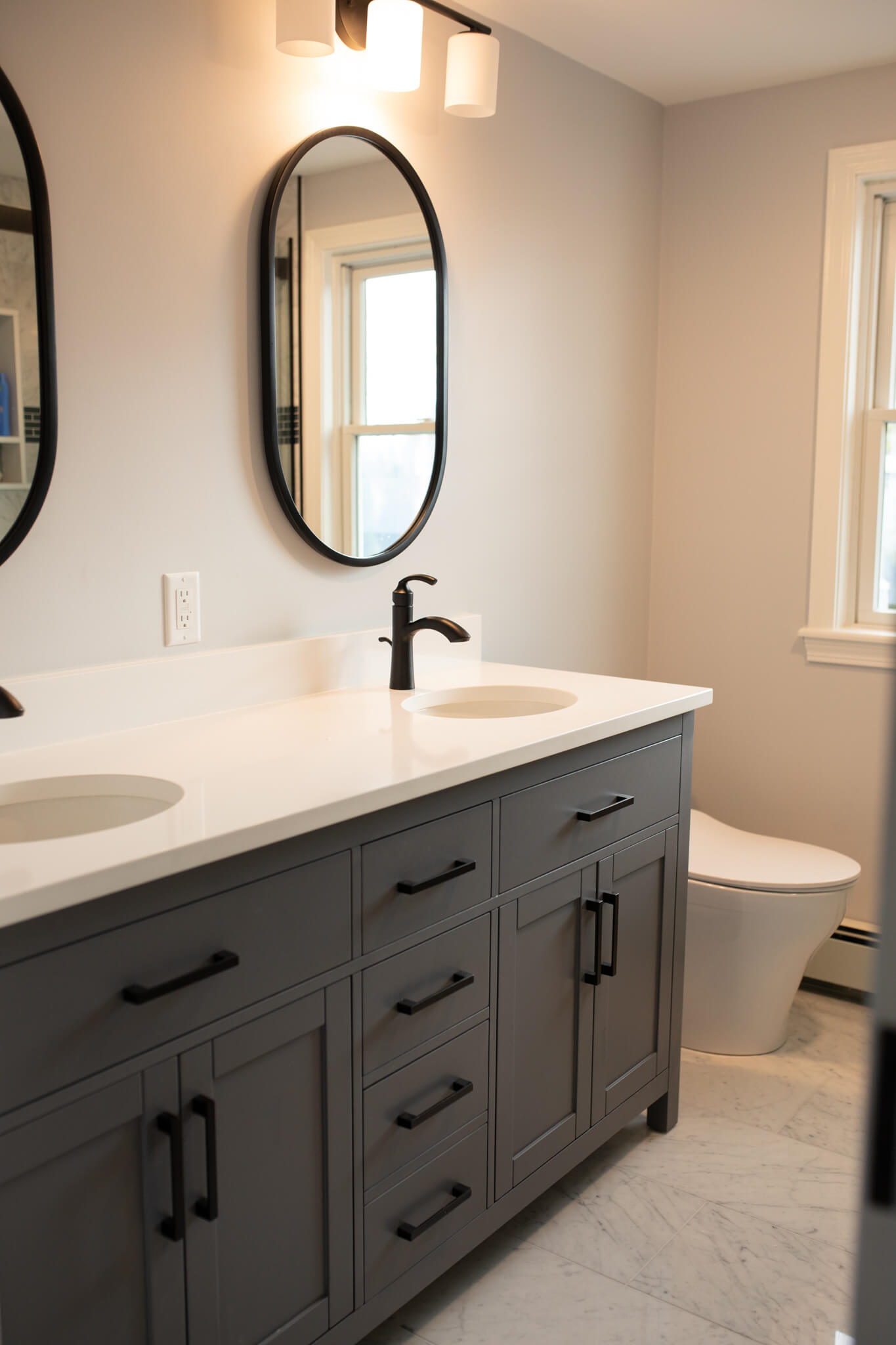 Bathroom remodel with double sinks, dark gray cabinets and black finishes