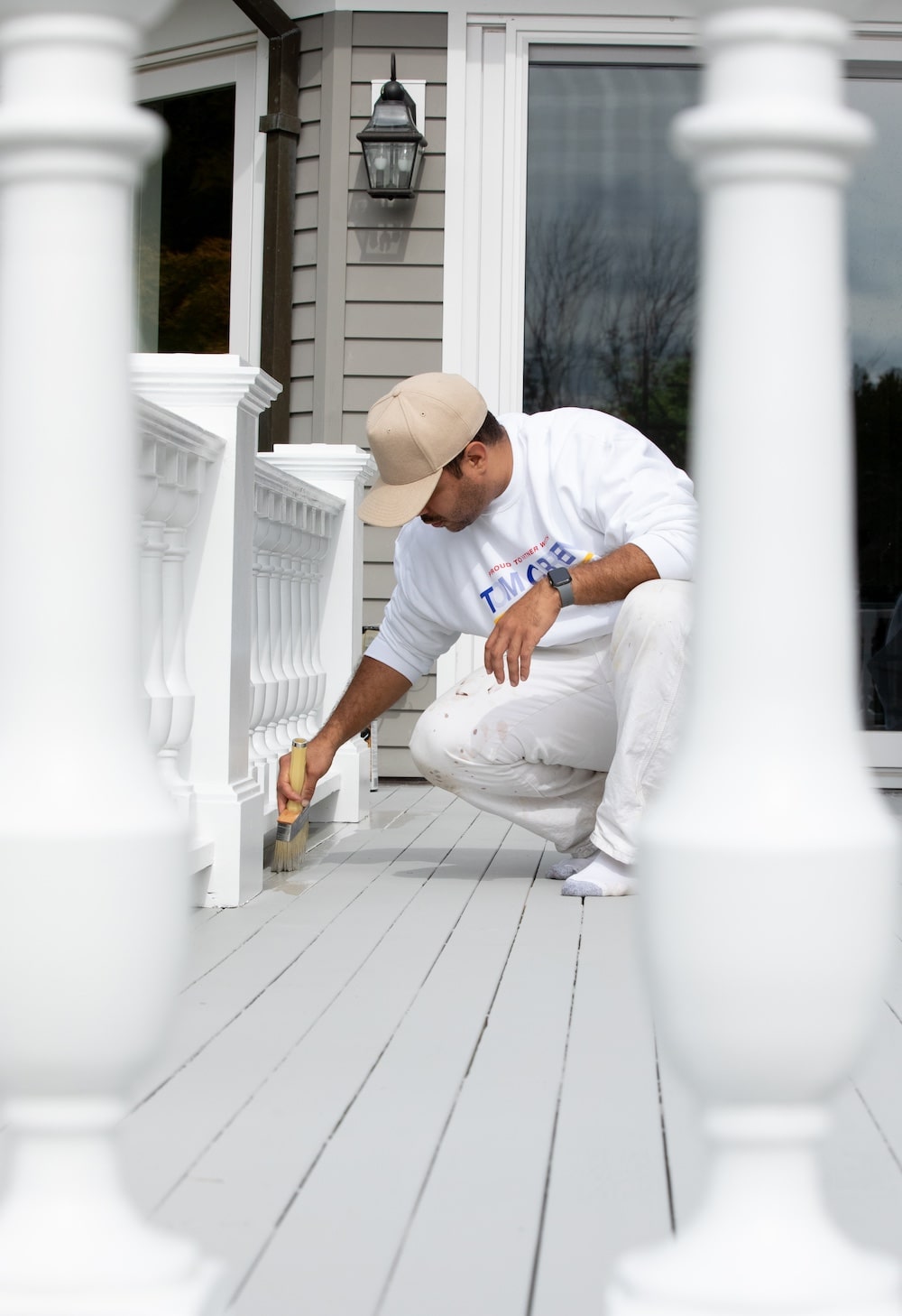Tom Curren employee painting a deck light gray
