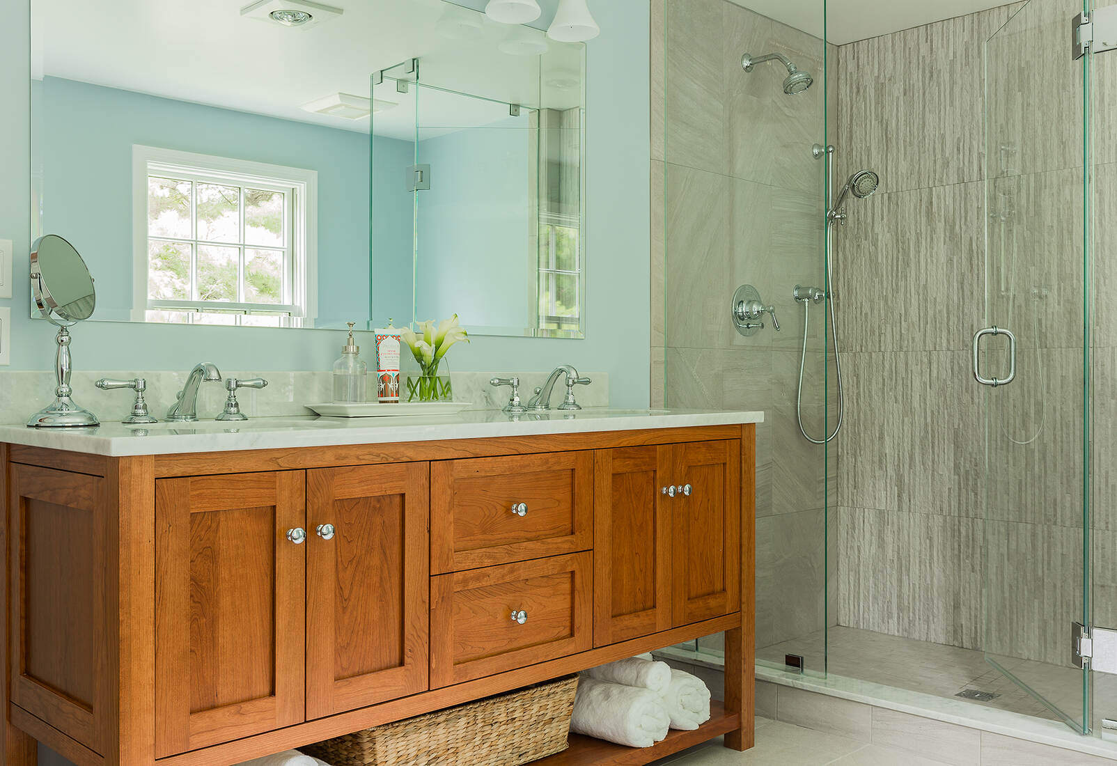 Modern bathroom remodel in Lexington, MA by Tom Curren, featuring a wood double vanity and a spacious glass-enclosed shower