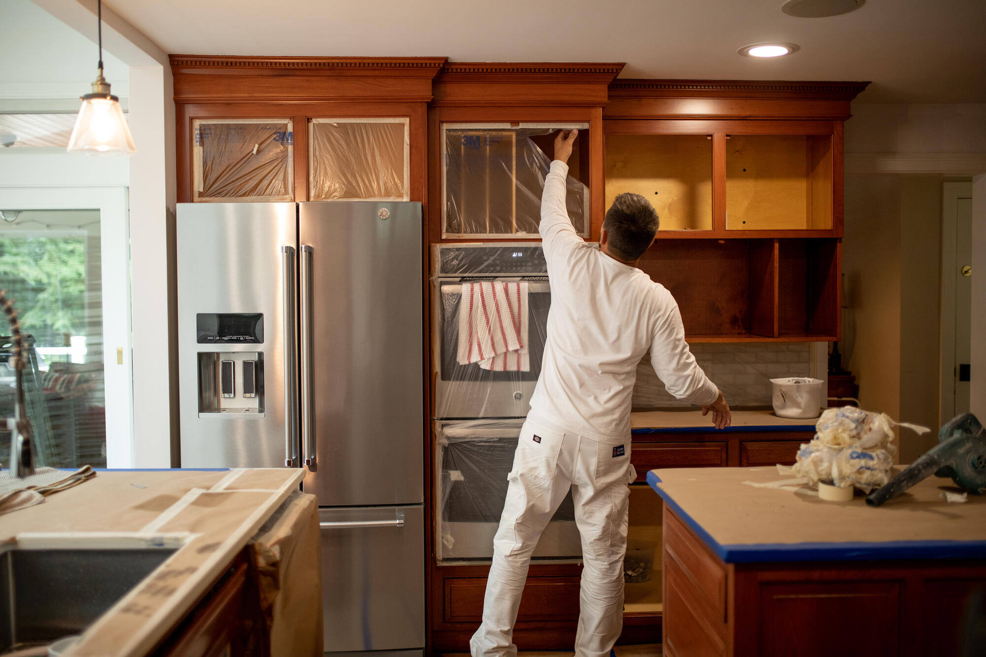 professional painter refinishing wooden kitchen cabinets as part of a cabinet painting project by Tom Curren Companies in West Metro Boston