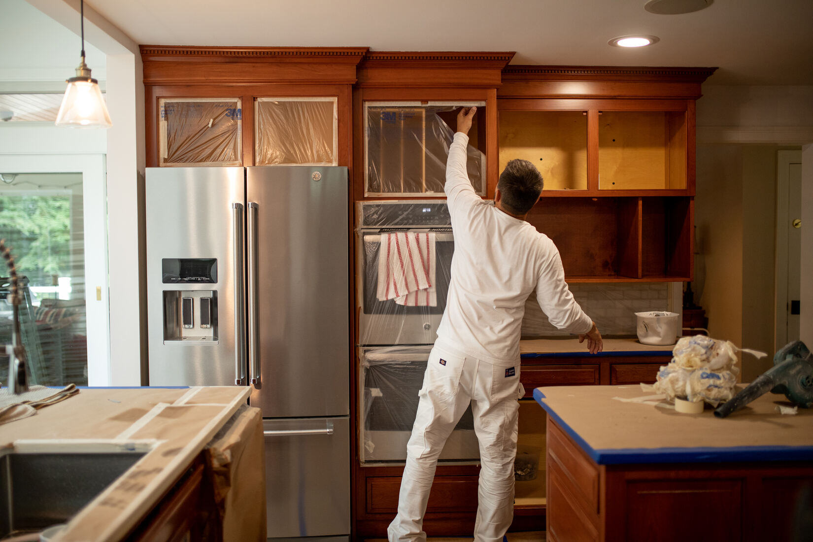 professional painter refinishing wooden kitchen cabinets as part of a cabinet painting project by Tom Curren Companies in West Metro Boston professional painter refinishing wooden kitchen cabinets as part of a cabinet painting project by Tom Curren Companies in West Metro Boston