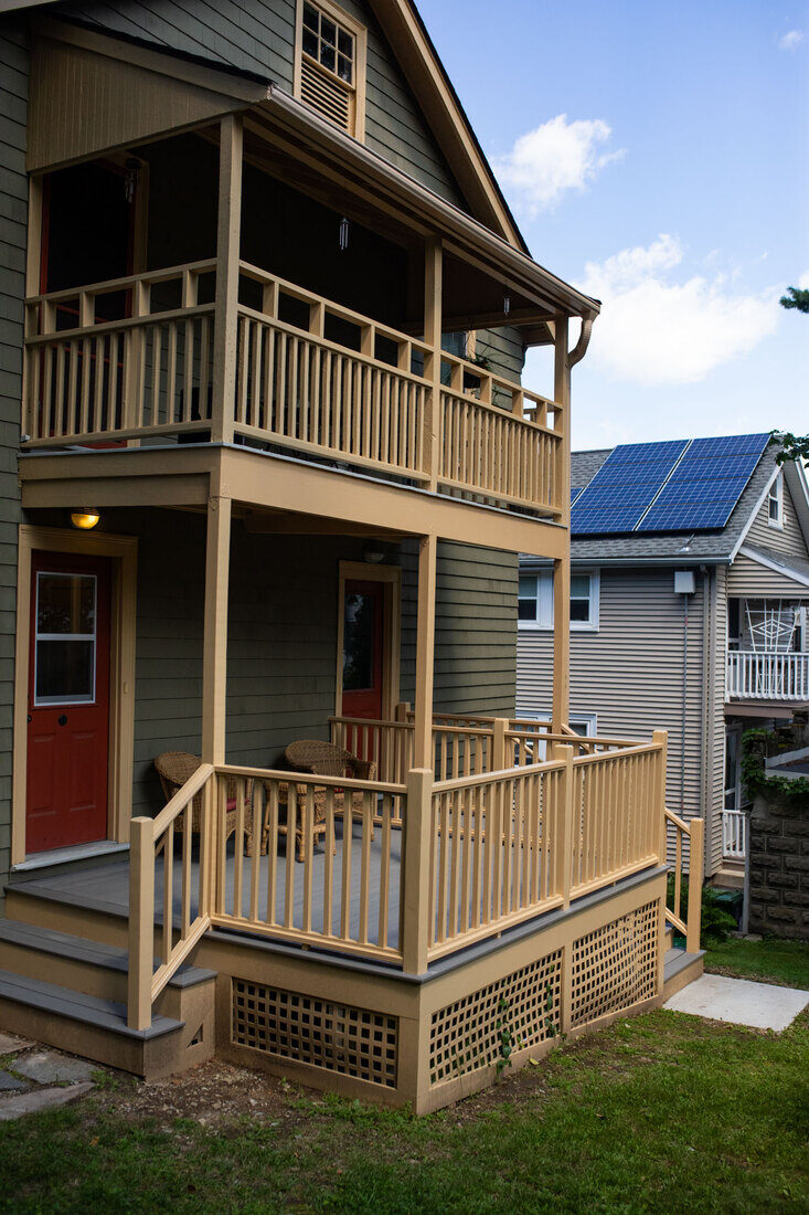 Charming two-story porch renovation with wooden railings, rebuilt by Tom Curren in Watertown, MA