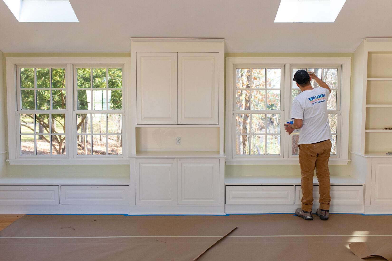 Painter in Sudbury, MA carefully painting walls near large windows for a clean, refreshed interior