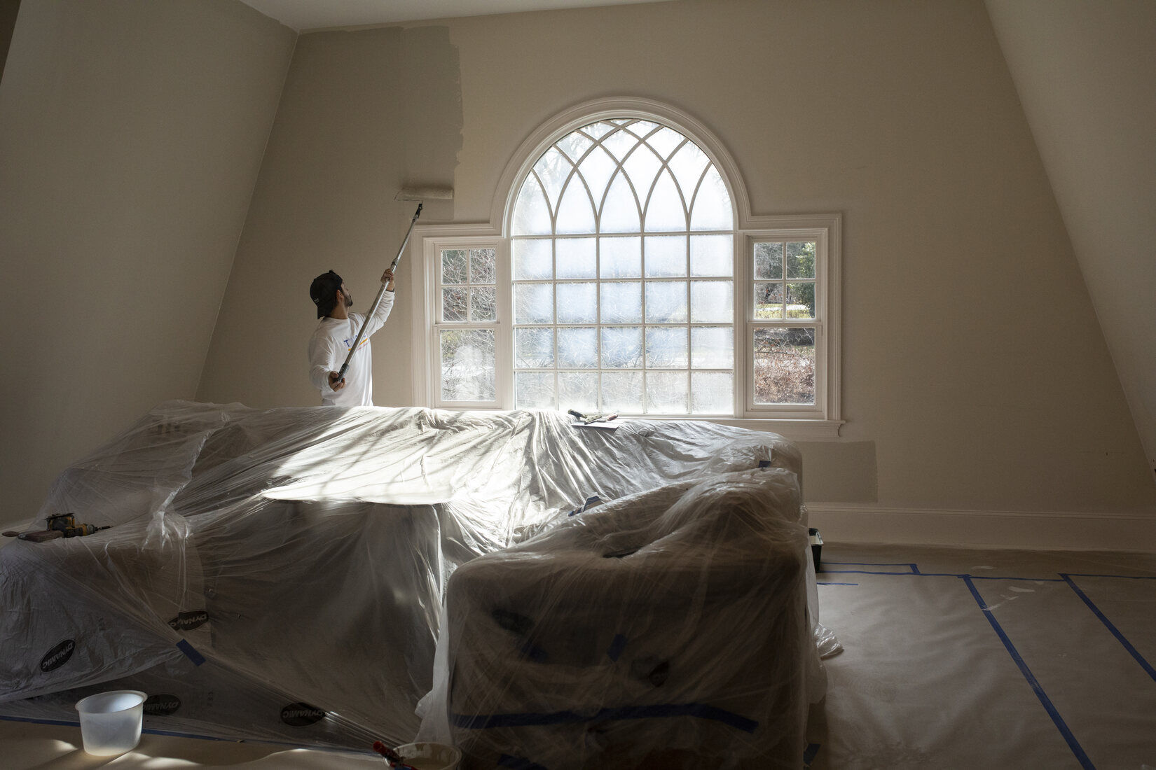 Professional interior painting in Lincoln, MA, with a painter applying a fresh coat of paint to a high-ceilinged room