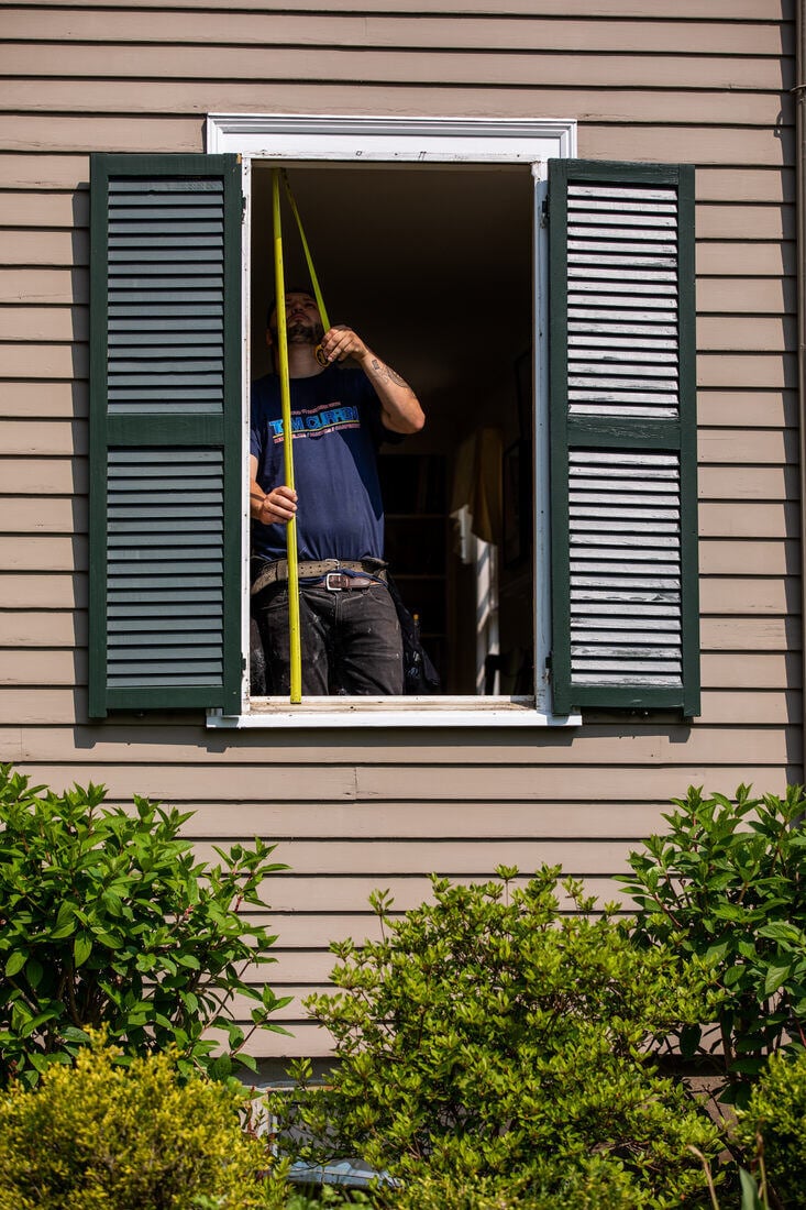 Home window renovation project in Needham, MA, with a contractor taking precise measurements