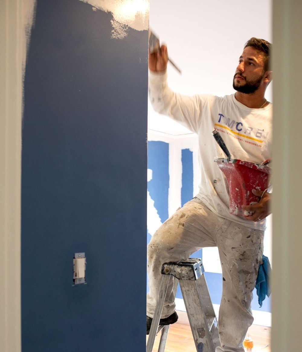 Tom Curren employee paints an interior room blue.