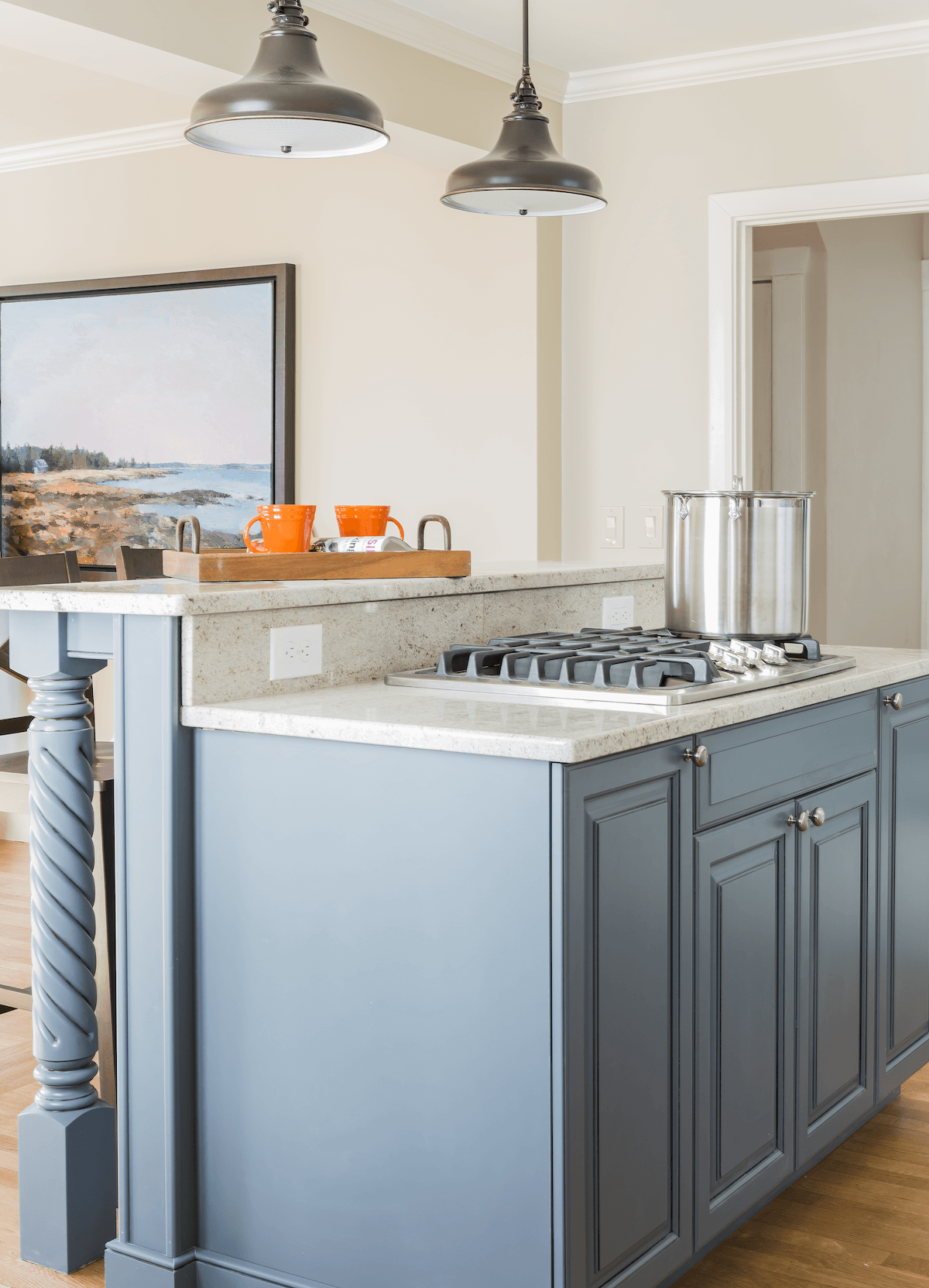 Kitchen stovetop with blue cabinets and pendent lighting.