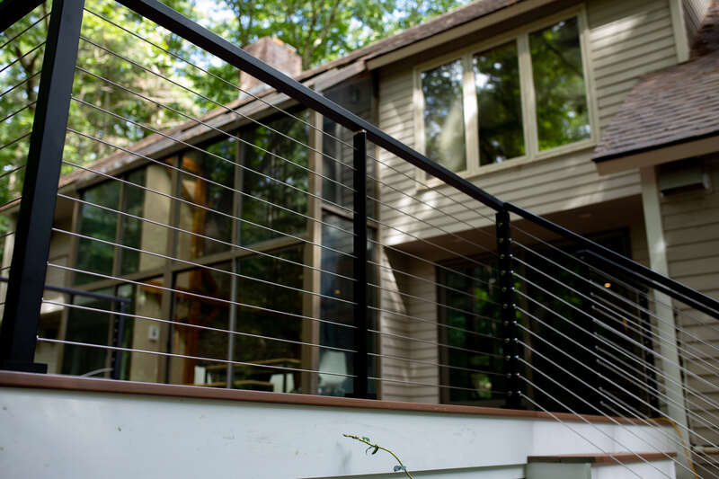 Close-up view of deck with black metal and wire railing.