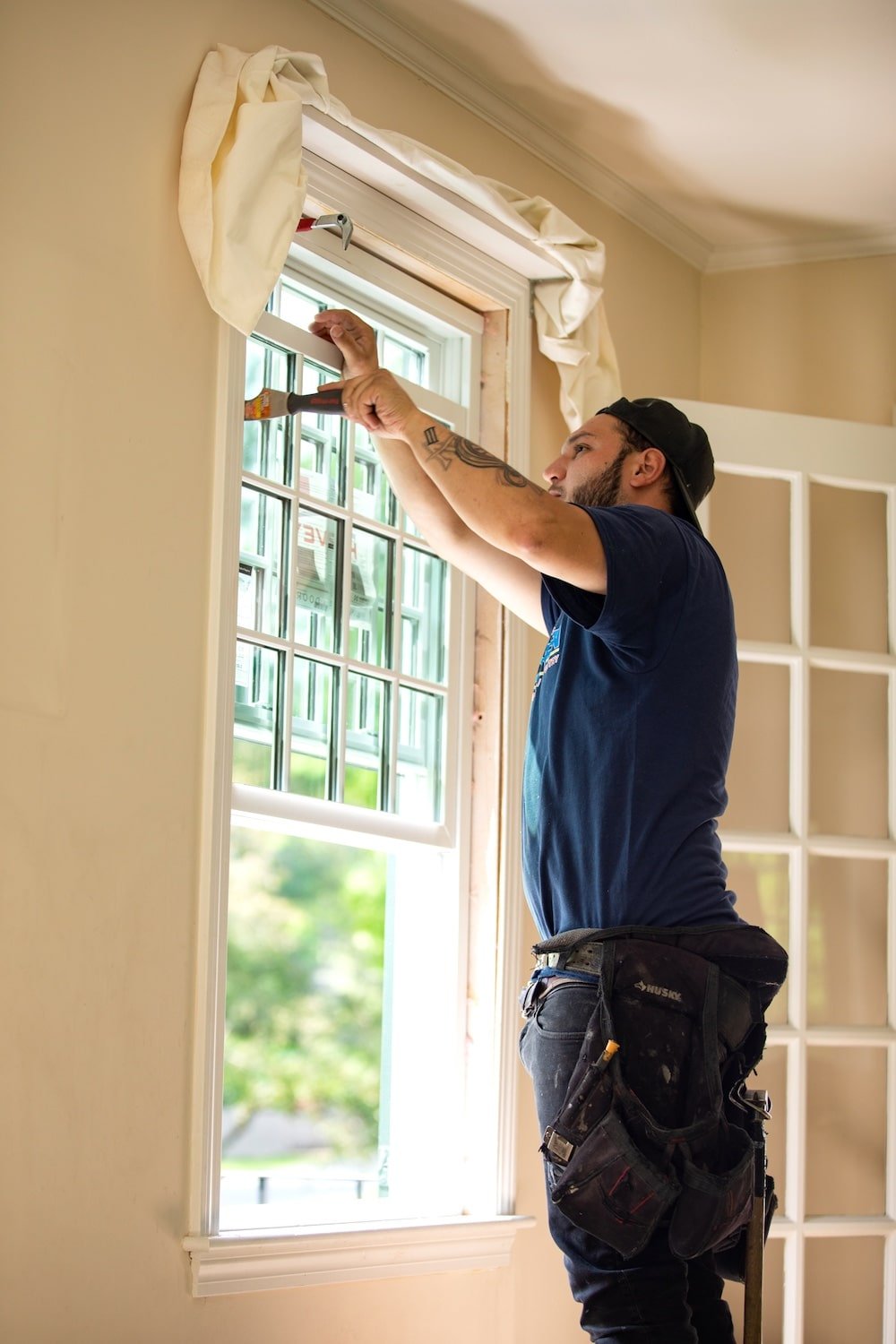 Tom Curren employee painting the trim around a window sill.